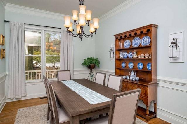 dining space featuring light hardwood / wood-style flooring, crown molding, and a chandelier