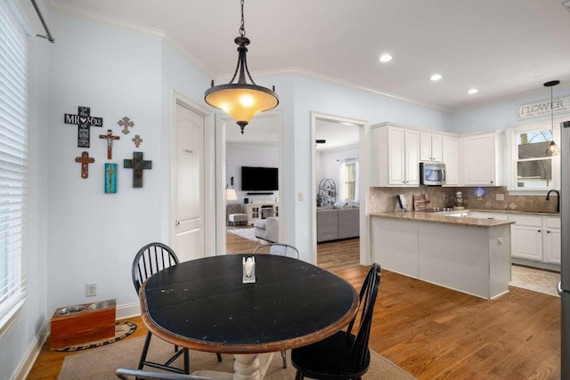 dining area with ornamental molding and light hardwood / wood-style flooring