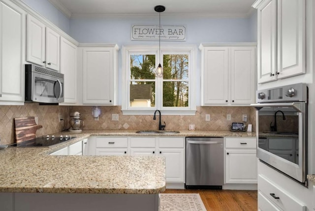 kitchen with stainless steel appliances, white cabinets, sink, and pendant lighting