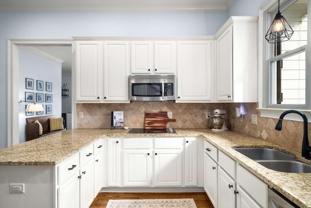 kitchen featuring sink, appliances with stainless steel finishes, hanging light fixtures, and white cabinetry