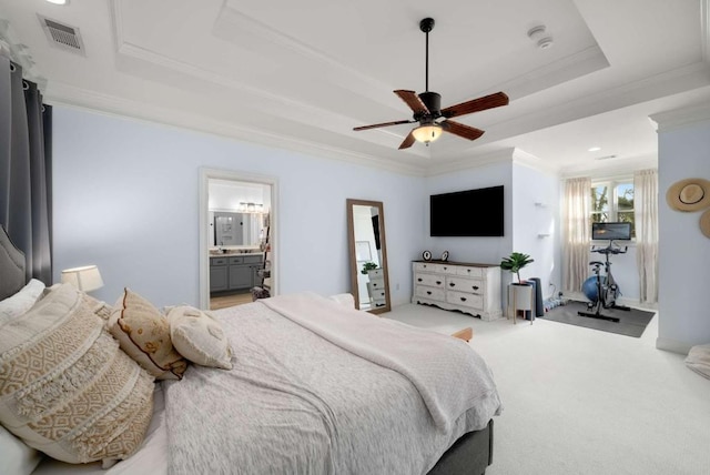 bedroom featuring ensuite bath, a raised ceiling, light colored carpet, crown molding, and ceiling fan