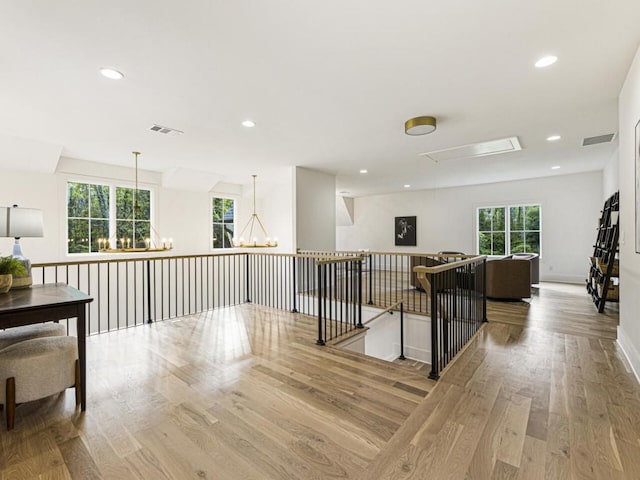 hallway featuring an inviting chandelier and light hardwood / wood-style floors