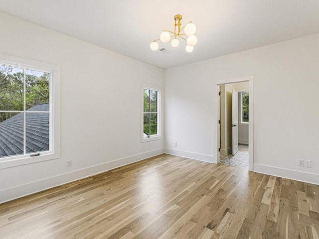 empty room featuring a chandelier and light hardwood / wood-style flooring