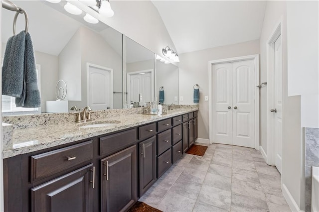4050 Danbury Farms Dr, Cumming, GA 30040 - bathroom with double vanity, vaulted ceiling, baseboards, and a sink