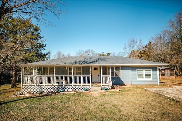 view of front of home with covered porch, a storage unit, and a front yard