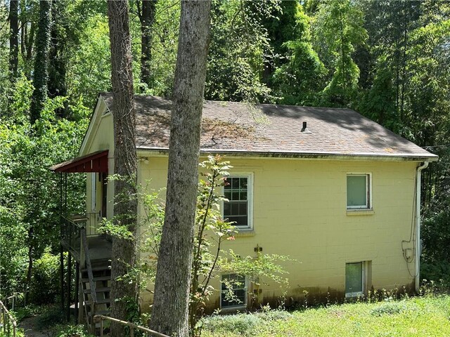 1783 Ridgewood Dr, Atlanta, GA 30307 - view of property exterior with concrete block siding, a shingled roof, and a wooded view