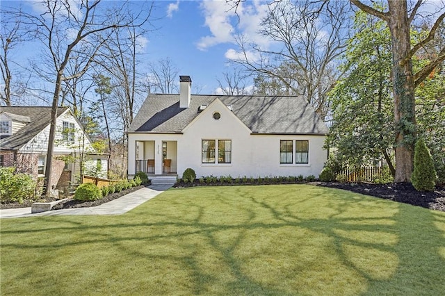 view of front of house with stucco siding, a chimney, and a front lawn