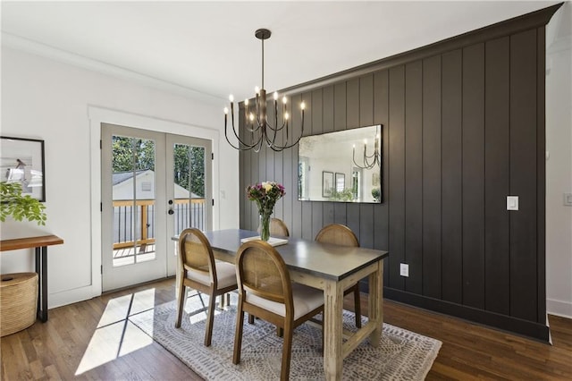 dining area featuring baseboards, ornamental molding, french doors, wood finished floors, and a notable chandelier