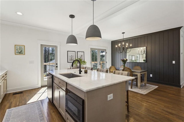 kitchen featuring a sink, dark wood-type flooring, black microwave, a kitchen bar, and a wealth of natural light