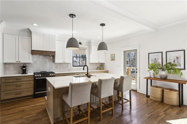 kitchen with an island with sink, a sink, tasteful backsplash, gas range oven, and light countertops