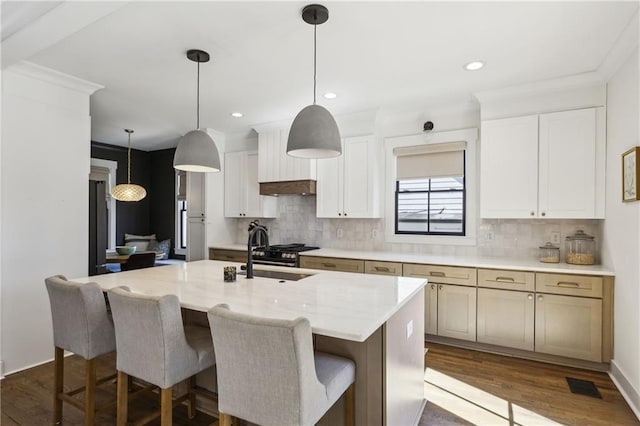 kitchen featuring visible vents, a sink, dark wood finished floors, decorative backsplash, and a kitchen island with sink