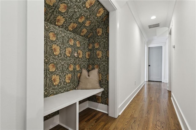 hallway with visible vents, wallpapered walls, baseboards, and wood finished floors