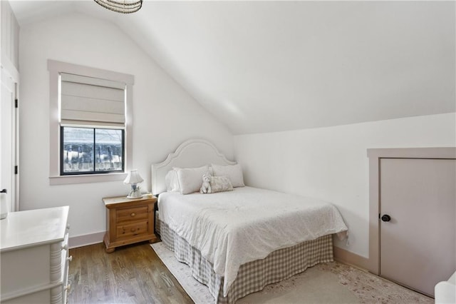 bedroom featuring baseboards, lofted ceiling, and wood finished floors