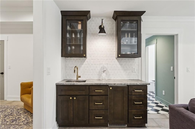 bar with indoor wet bar, decorative backsplash, light floors, and a sink