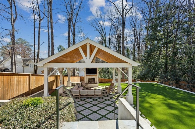 view of patio featuring a gazebo, exterior fireplace, and a fenced backyard