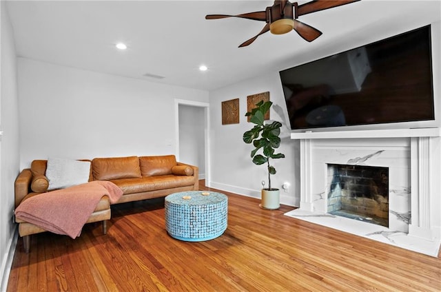 living room featuring recessed lighting, a fireplace, baseboards, and wood finished floors