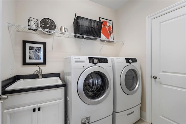 clothes washing area featuring cabinets, washer and clothes dryer, and sink