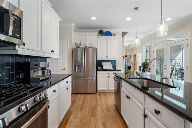 kitchen featuring white cabinetry, tasteful backsplash, stainless steel appliances, sink, and hanging light fixtures