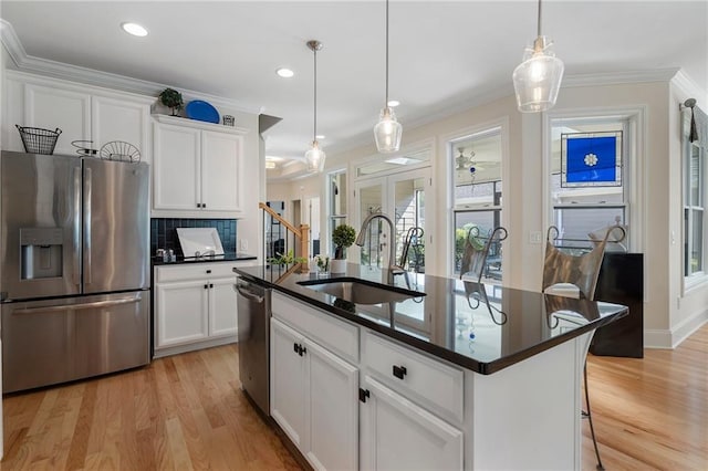 kitchen featuring pendant lighting, sink, appliances with stainless steel finishes, a center island with sink, and white cabinets