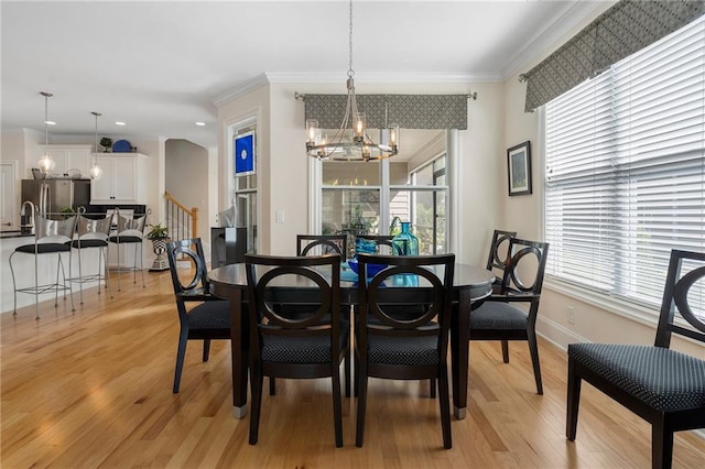 dining space featuring ornamental molding, plenty of natural light, an inviting chandelier, and light hardwood / wood-style floors