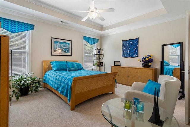 carpeted bedroom featuring ceiling fan, ornamental molding, and a tray ceiling