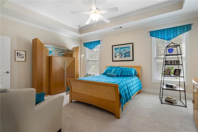 carpeted bedroom featuring a tray ceiling, crown molding, and ceiling fan