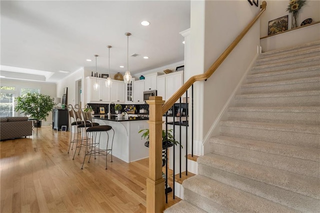 staircase with crown molding, sink, and hardwood / wood-style flooring