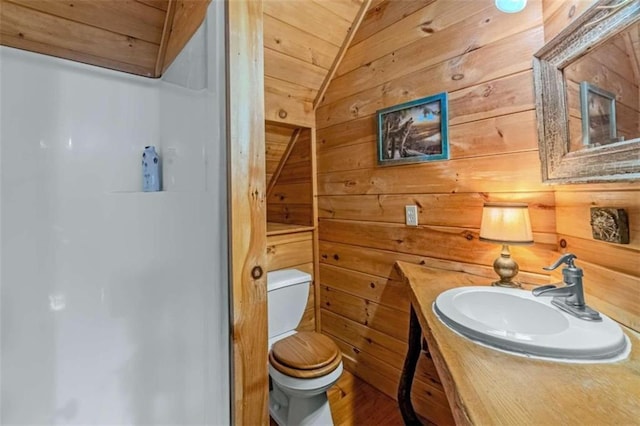 bathroom featuring vanity, toilet, wooden walls, and vaulted ceiling