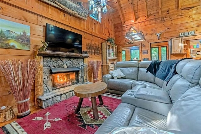 living room featuring ceiling fan, beamed ceiling, wooden walls, and a fireplace