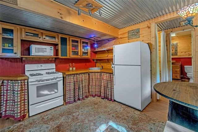 kitchen featuring hardwood / wood-style floors, white appliances, and wooden walls