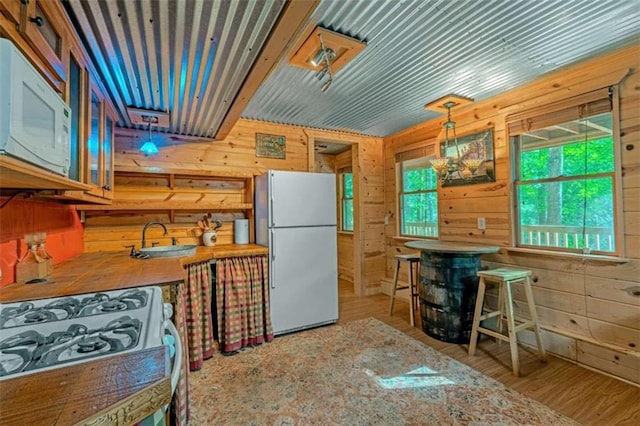 kitchen featuring wood walls, white appliances, hardwood / wood-style floors, and plenty of natural light