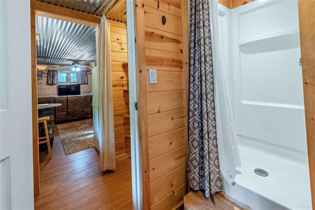 bathroom featuring hardwood / wood-style flooring, curtained shower, and wooden walls