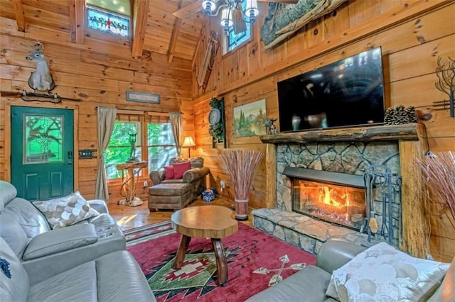 living room with beamed ceiling, high vaulted ceiling, wood walls, a stone fireplace, and wooden ceiling