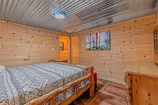 bedroom with hardwood / wood-style floors and wood walls