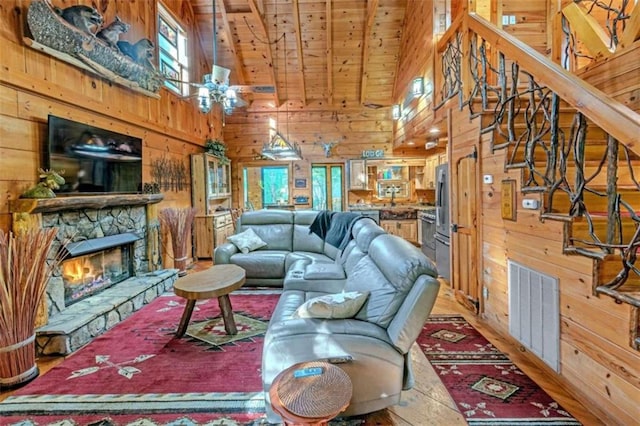 living room featuring a stone fireplace, wood walls, high vaulted ceiling, and wooden ceiling