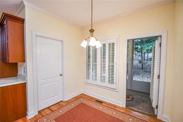 unfurnished dining area with light wood-type flooring, crown molding, and a chandelier