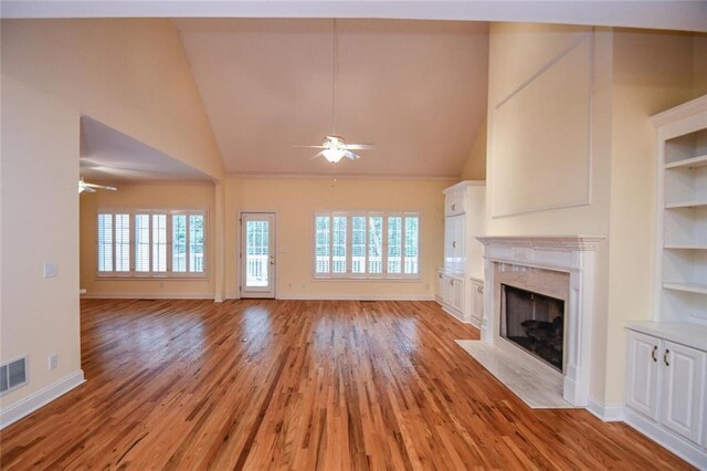 unfurnished living room featuring a premium fireplace, ceiling fan, and a healthy amount of sunlight