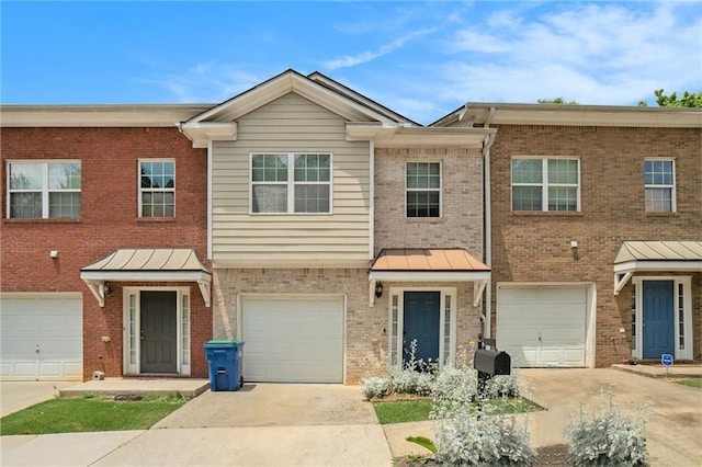 multi unit property with metal roof, a garage, brick siding, driveway, and a standing seam roof