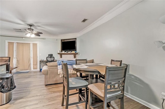 dining area with light wood-style flooring, a ceiling fan, visible vents, and crown molding