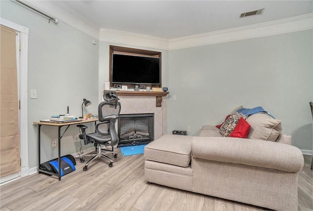 living area with a fireplace, wood finished floors, visible vents, baseboards, and crown molding