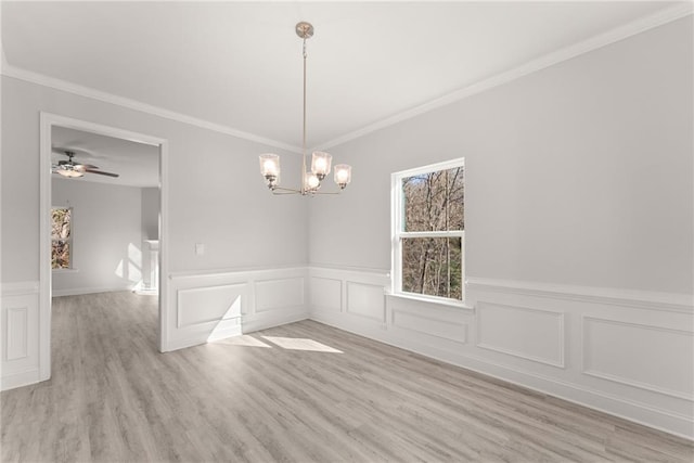 spare room featuring ceiling fan with notable chandelier, light wood-type flooring, ornamental molding, and wainscoting