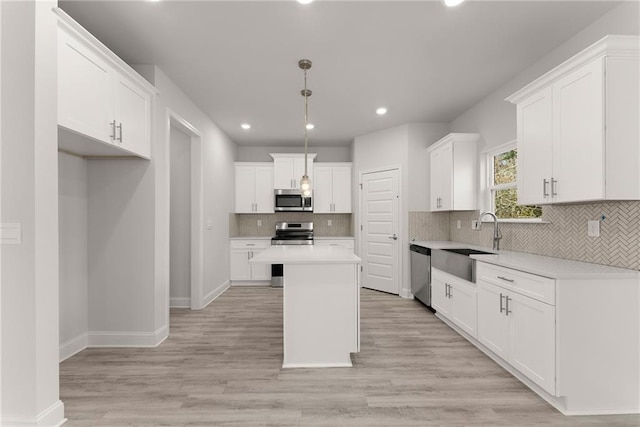 kitchen featuring white cabinets, a sink, stainless steel appliances, and a kitchen island