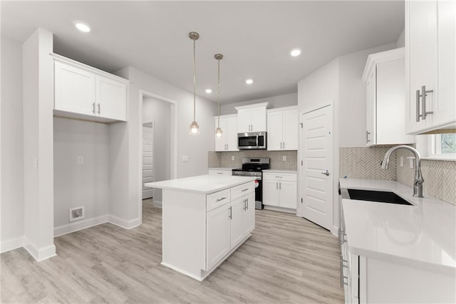 kitchen with white cabinetry, a sink, stainless steel appliances, and a kitchen island