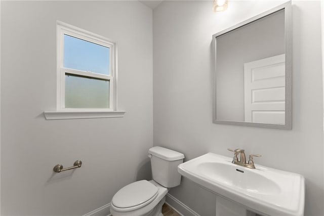 bathroom featuring baseboards, a sink, and toilet