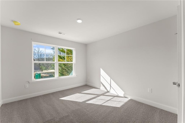 carpeted spare room featuring baseboards and visible vents