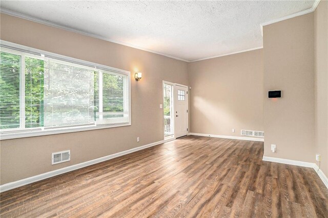 spare room featuring a textured ceiling, dark hardwood / wood-style floors, and ornamental molding