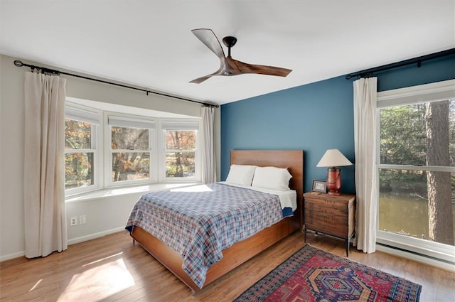 bedroom with a ceiling fan, wood finished floors, and baseboards
