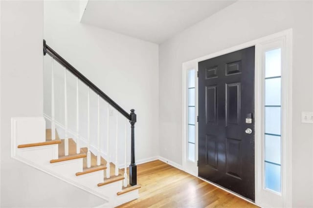 foyer with stairway, baseboards, and wood finished floors