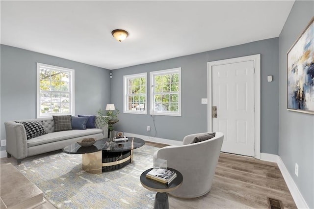 living area with visible vents, plenty of natural light, baseboards, and wood finished floors