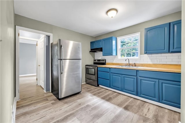 kitchen with a sink, blue cabinetry, range hood, appliances with stainless steel finishes, and decorative backsplash